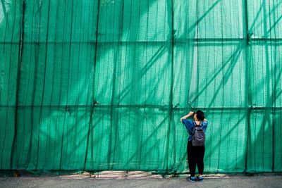 Full length of young woman standing against wall