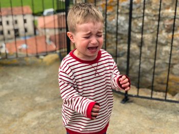 Boy crying while standing on footpath