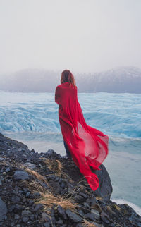 Elegant lady with red fabric on rock scenic photography