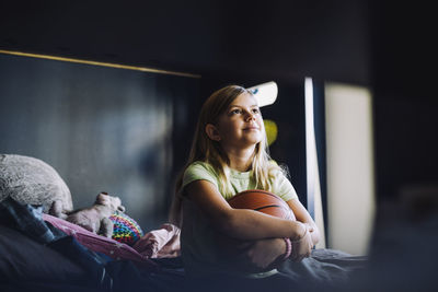 Portrait of young woman sitting on bed at home