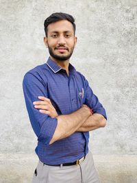 Portrait of young man standing against wall