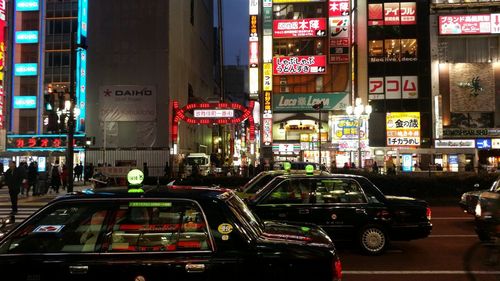 Taxis on street against buildings in city at night