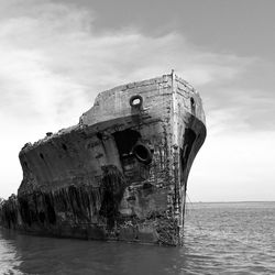 Low angle view of damaged boat on sea against sky