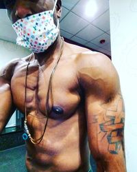 Midsection of shirtless man looking at camera