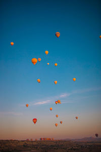 Low angle view of balloons against sky during sunset