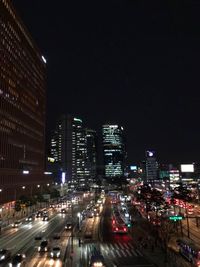 Illuminated city street and buildings against sky at night