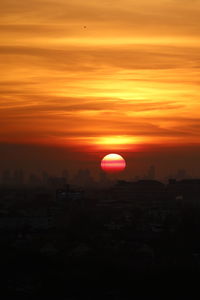 Silhouette built structure against orange sky during sunset