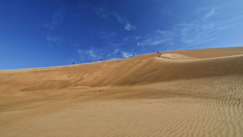 Sand dunes in desert against blue sky