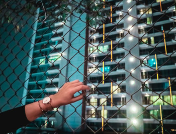 Cropped image of hand on chainlink fence