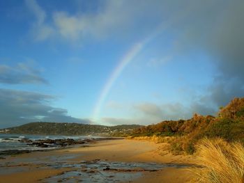 Scenic view of rainbow over beach against sky