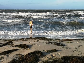 Rear view of person on beach against sky