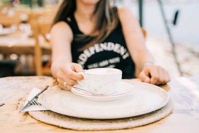 Midsection of woman holding coffee on table