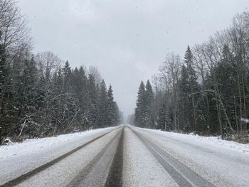 Road amidst snow covered trees against sky