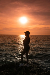 Silhouette person standing on beach during sunset