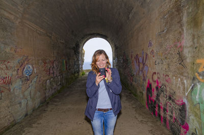 Full length of woman standing against graffiti wall