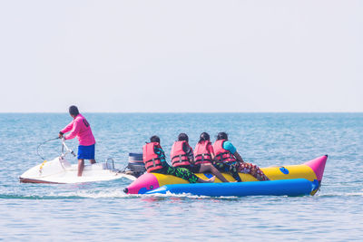 Man on jet boat by women rafting in sea