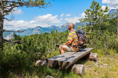 Man sitting on plant by land against sky