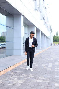 Young businessman standing against building