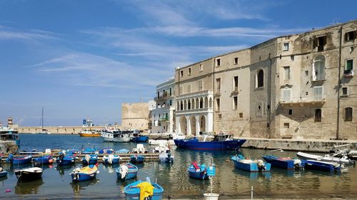 Boats moored in canal by buildings in city