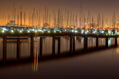 A tall ladder leading from the pier to the water, with ships in the background at dusk