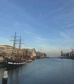 Sailboats in harbor by sea against sky in city