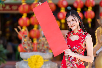 Midsection of woman holding red while standing against blurred background
