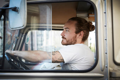 Side view of young man driving food truck in city