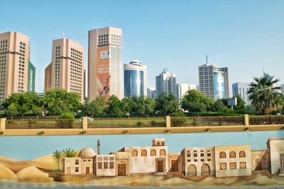 Buildings by swimming pool in city against clear sky