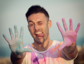 Man playing with powdered paint while standing against sky