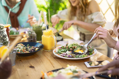 Midsection of friends eating food at table