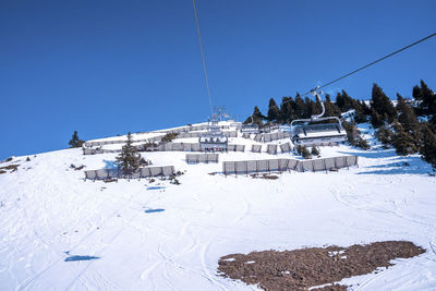 Ski lift over scenic snow covered mountain slope against blue sky