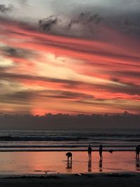 People on beach against sky during sunset