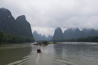 Scenic view of river by mountains against sky