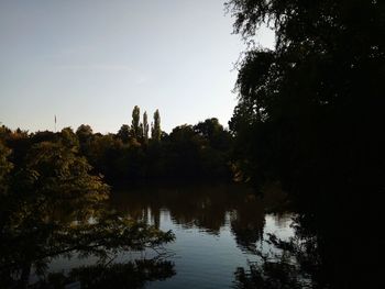 Silhouette trees by lake against sky during sunset