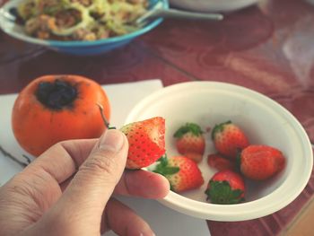 Close-up of hand holding fruits in plate