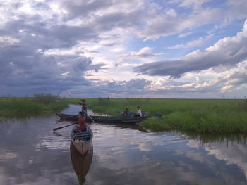 Man and woman in boat on water against sky