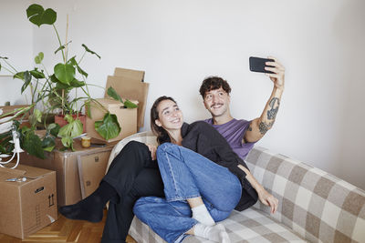 Young couple on sofa taking selfie