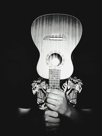 Man holding guitar against black background