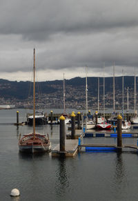 Sailboats moored in sea against sky