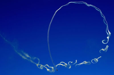 Low angle view of contrails at blue sky