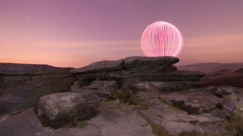 Light painting by rock formations against sky at night