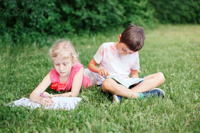 Cute kids studying sitting on grass