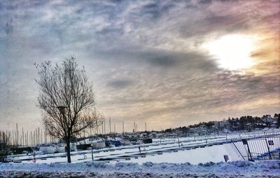 Snow covered landscape against cloudy sky