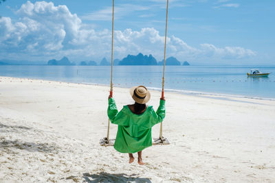 Rear view of woman swinging at beach