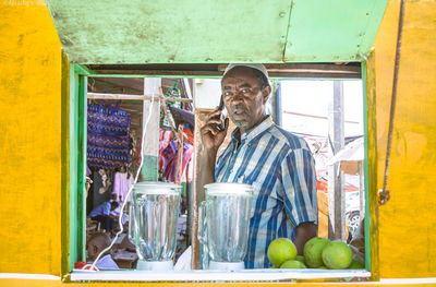 Portrait of fourty man standing on his shop talking with phone 