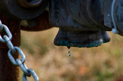 Close-up of water drop falling from rusty metal