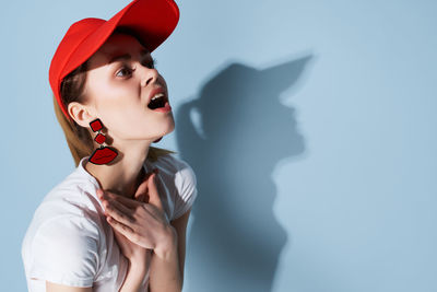 Portrait of young woman standing against wall