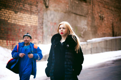 Young man and woman walking on road during winter