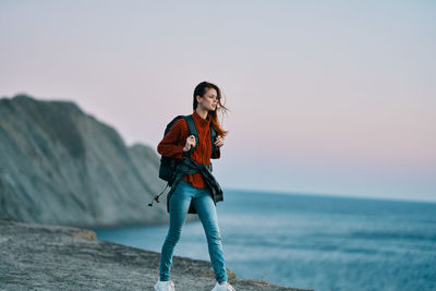 Full length of young woman standing in sea against clear sky