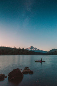 Man kayaking in lake against sky